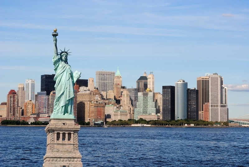 picture of the statue of liberty with the new York skyline and water in the background